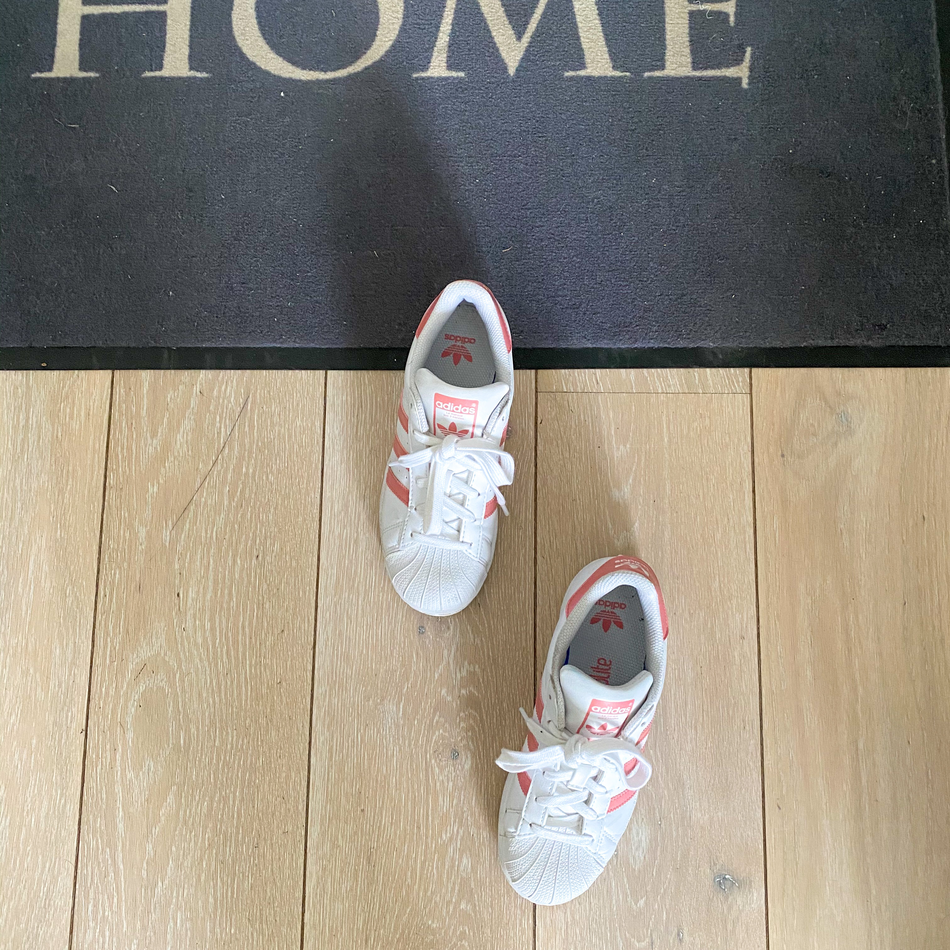Image of sneakers on welcome home mat; meant to refer to confinement