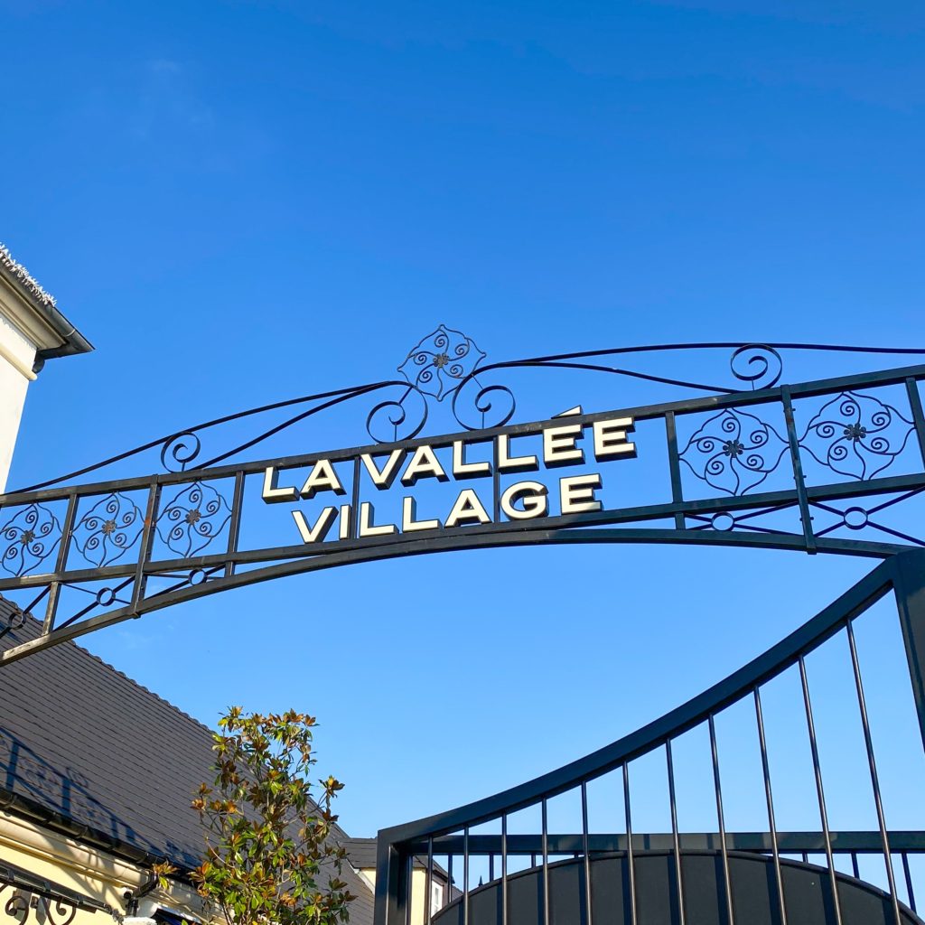 Image of the entrance to La Vallee Village - an outdoor shopping mall of designer and luxury boutiques. One of three great places you can purchase designer items on a budget.